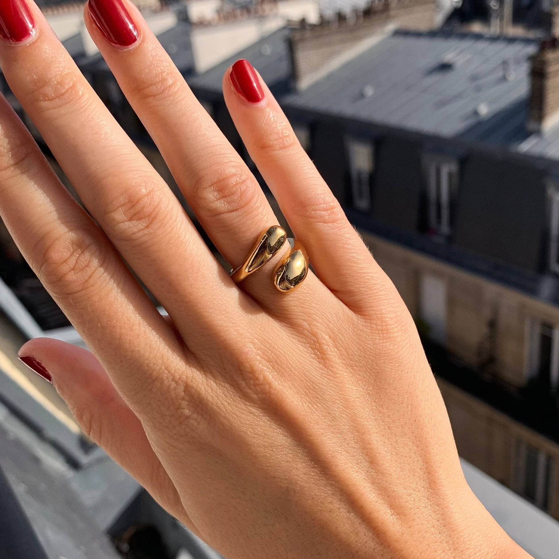Trendiger verstellbarer Ring aus Edelstahl auf einer Hand mit rotem Nagellack.